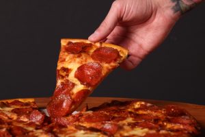 hand holding a slice of pepperoni pizza